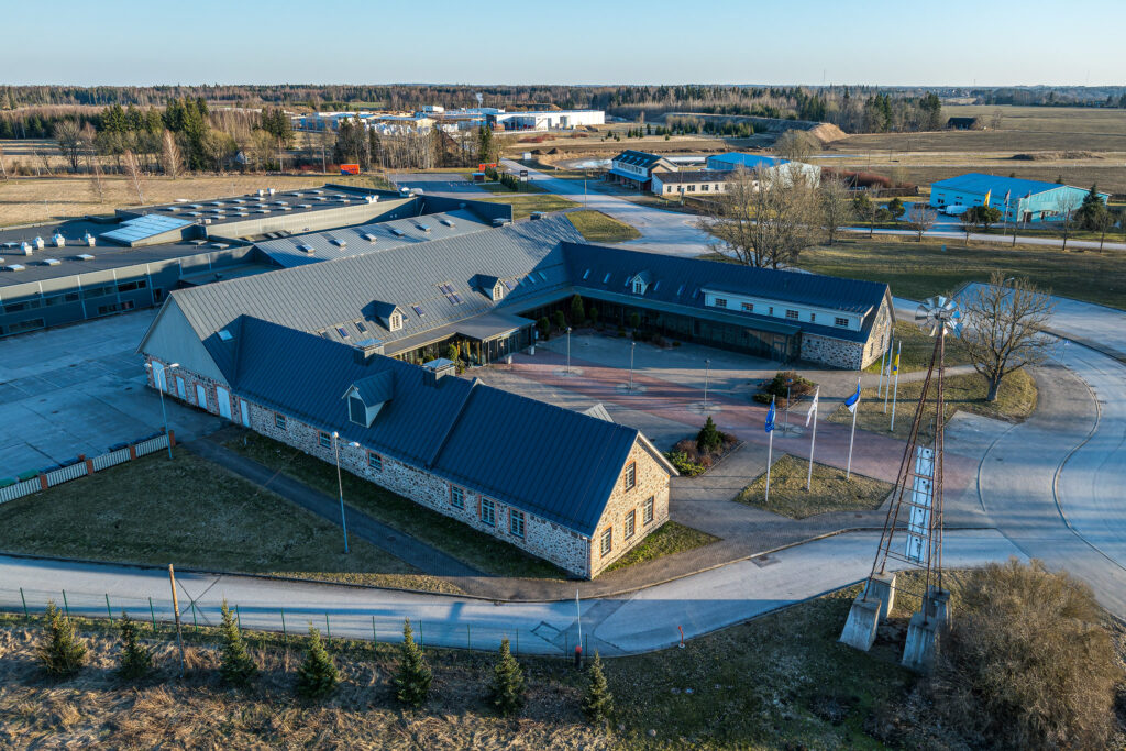Viljandi Kutseõppekeskuse peahoone ja õppehooned linnulennult, esiplaanil ajalooline kivimaja ja tuulik.